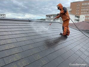 屋根を高圧洗浄している職人の画像